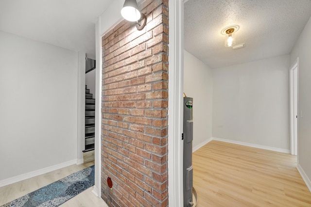 hallway featuring baseboards, a textured ceiling, wood finished floors, and stairway
