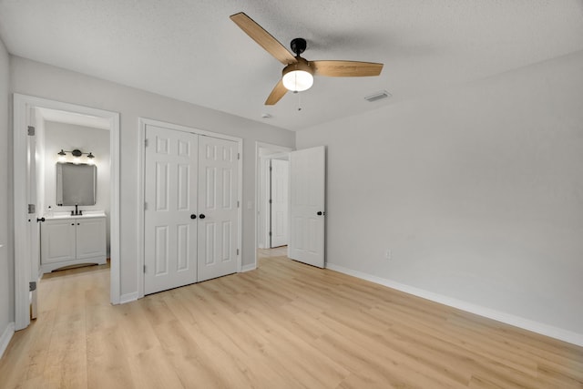 unfurnished bedroom featuring ceiling fan, light wood-style flooring, baseboards, visible vents, and a closet