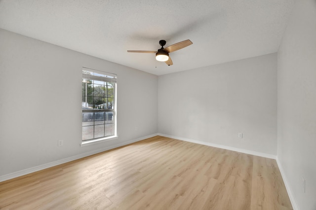 spare room featuring a ceiling fan, baseboards, a textured ceiling, and light wood-style floors