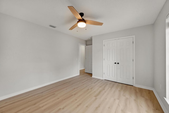 unfurnished bedroom featuring visible vents, a closet, wood finished floors, baseboards, and ceiling fan