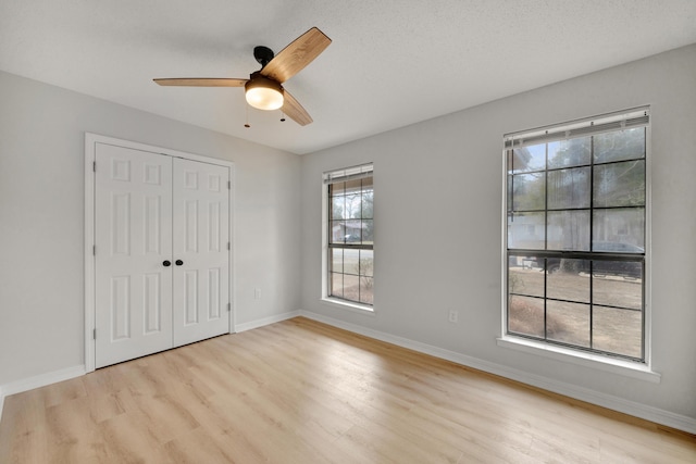 unfurnished bedroom featuring baseboards, ceiling fan, light wood-style flooring, and a closet