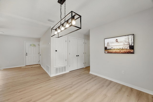 unfurnished dining area with baseboards, visible vents, wood finished floors, and vaulted ceiling