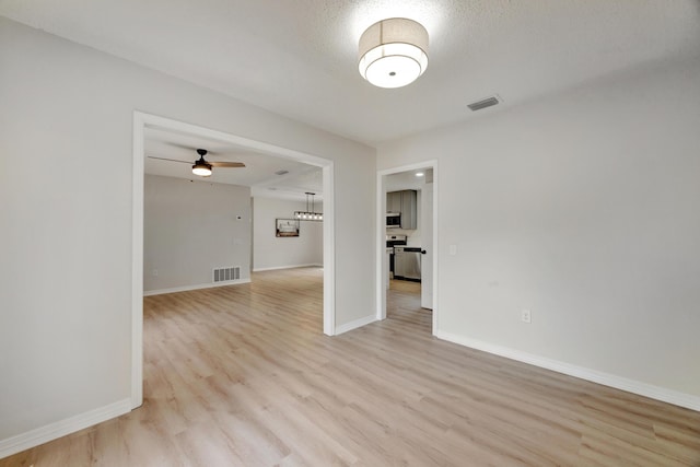 unfurnished room featuring baseboards, ceiling fan, light wood-style flooring, and visible vents
