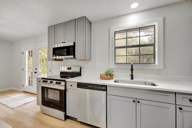 kitchen featuring a sink, appliances with stainless steel finishes, gray cabinetry, and a textured ceiling