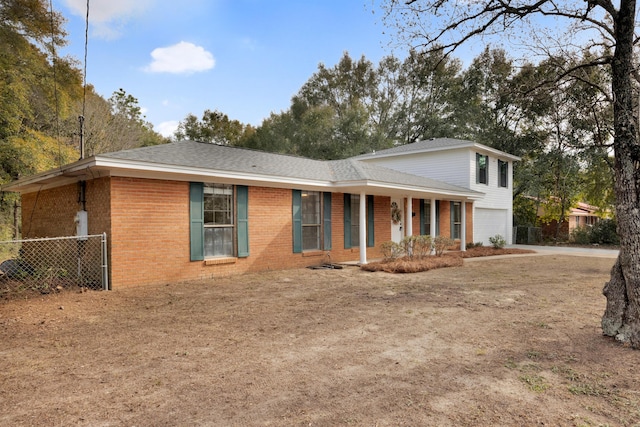 split level home with brick siding, an attached garage, fence, and a porch