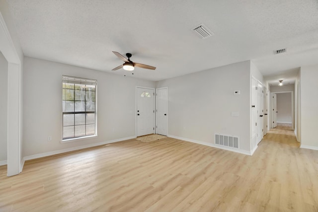 unfurnished living room featuring ceiling fan, visible vents, and light wood-style floors