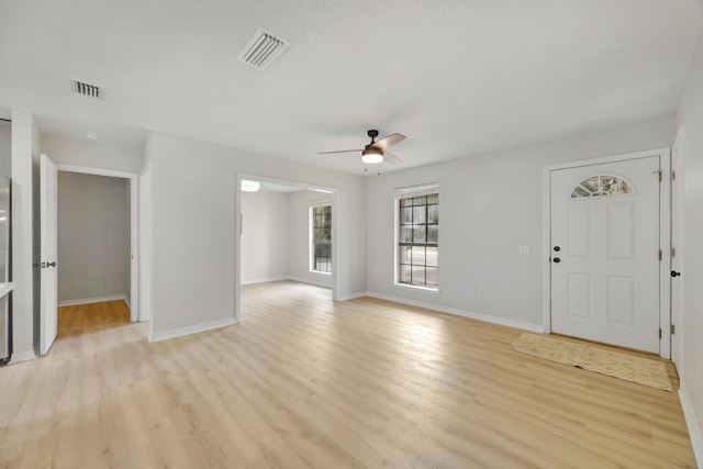 unfurnished living room featuring a ceiling fan, baseboards, visible vents, and light wood-style flooring