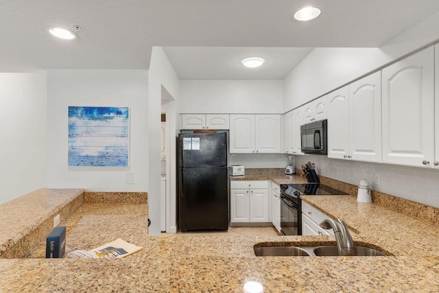 kitchen with black appliances, a sink, light stone countertops, white cabinetry, and recessed lighting