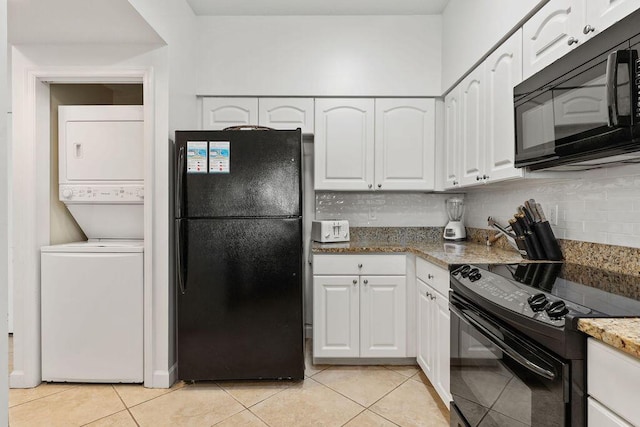 kitchen featuring black appliances, stacked washer / drying machine, and white cabinets
