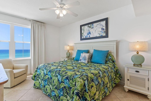 bedroom featuring light tile patterned floors, a water view, ceiling fan, and baseboards