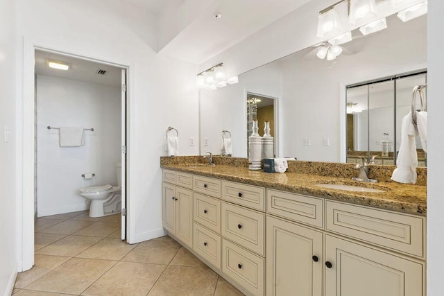 bathroom with tile patterned flooring, toilet, double vanity, ceiling fan, and baseboards