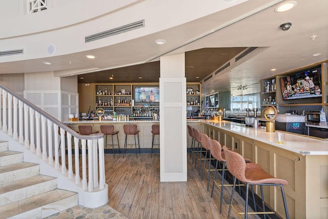 community bar area featuring wood finished floors, recessed lighting, and stairs