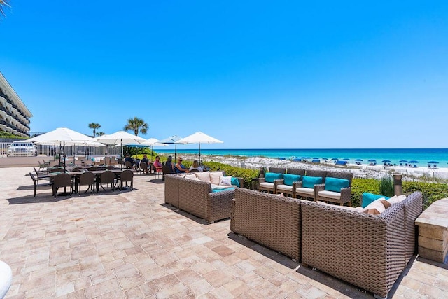 view of patio / terrace featuring an outdoor living space, view of water and beach, and outdoor dining area