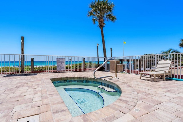 view of swimming pool with a hot tub, fence, a water view, and a patio area