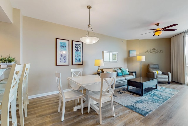 dining space featuring baseboards, a ceiling fan, and wood finished floors