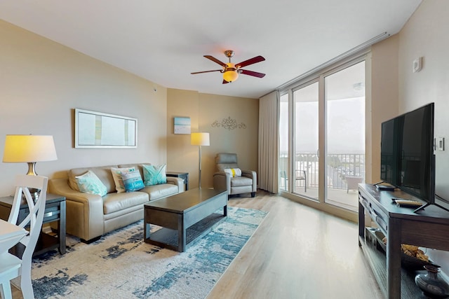 living area featuring ceiling fan, expansive windows, and wood finished floors