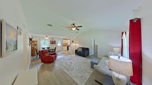 living room featuring ceiling fan, visible vents, lofted ceiling, and light wood-type flooring