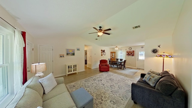 living area featuring ceiling fan, visible vents, baseboards, light wood finished floors, and lofted ceiling