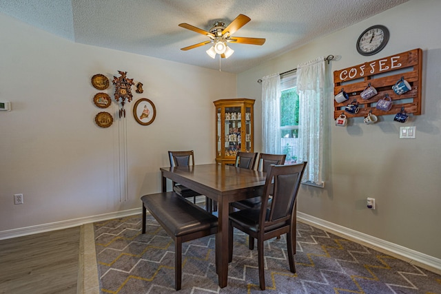 dining room with dark wood-style flooring, a textured ceiling, ceiling fan, and baseboards