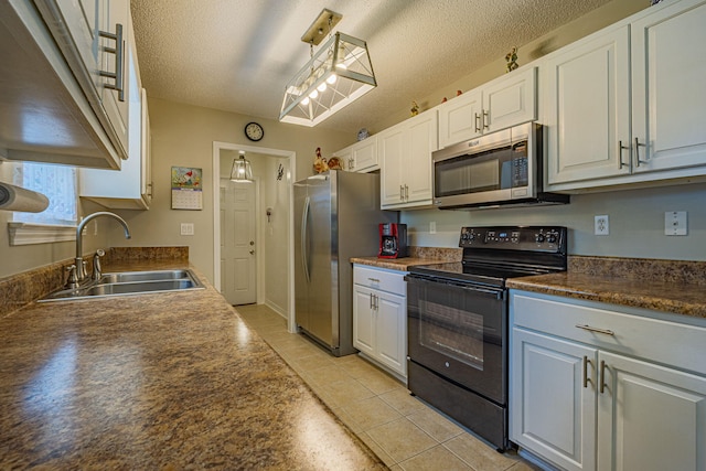kitchen with white cabinets, dark countertops, a sink, a textured ceiling, and stainless steel appliances