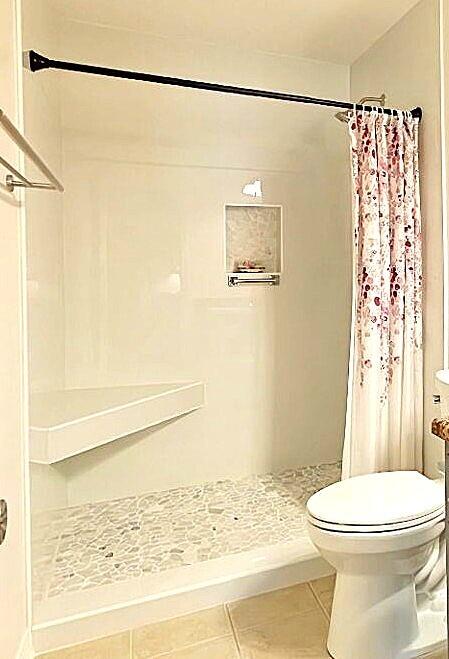 full bathroom with toilet, a shower stall, and tile patterned flooring