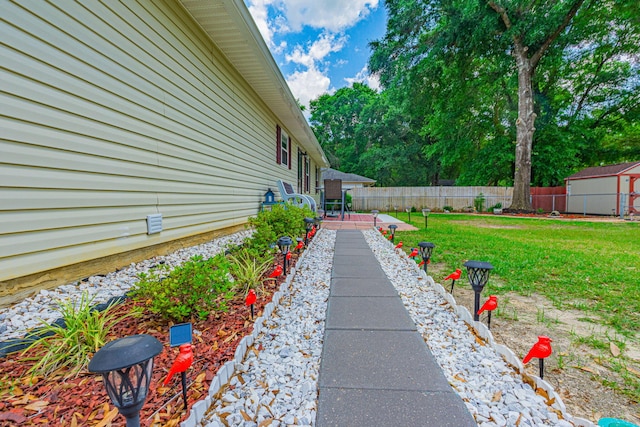 view of yard featuring an outbuilding, a patio area, fence, and a storage shed