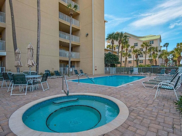 community pool featuring fence, a community hot tub, and a patio area