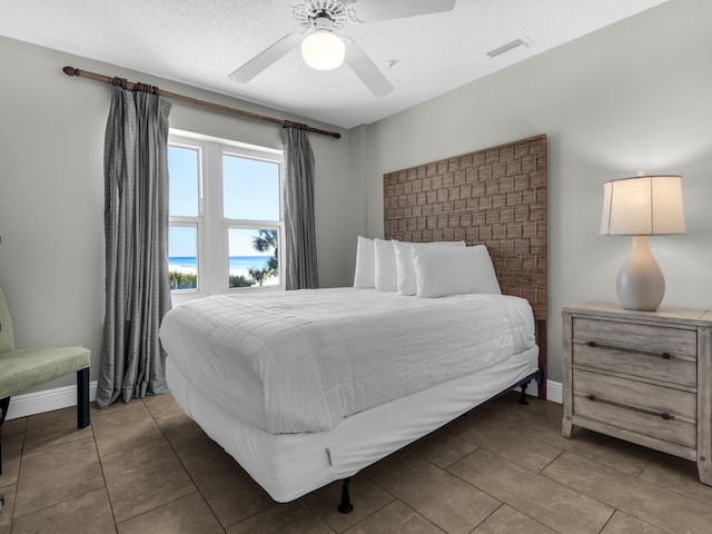 tiled bedroom with baseboards, visible vents, and ceiling fan