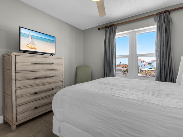 bedroom featuring a ceiling fan, a textured ceiling, and tile patterned floors