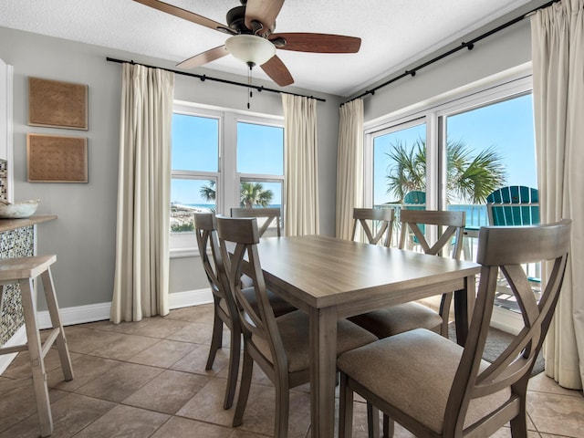 dining area with baseboards, a ceiling fan, a textured ceiling, and a wealth of natural light