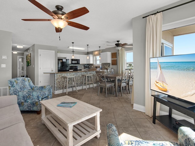 living room featuring a ceiling fan, baseboards, and light tile patterned floors