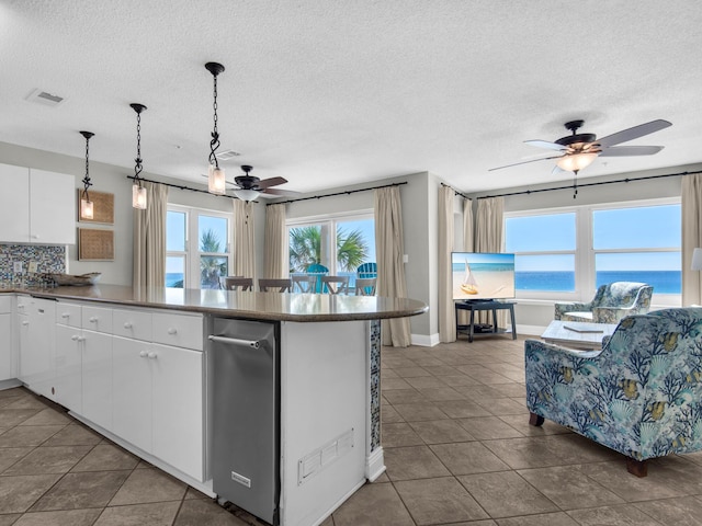 kitchen featuring tile patterned flooring, a peninsula, ceiling fan, a textured ceiling, and white cabinetry