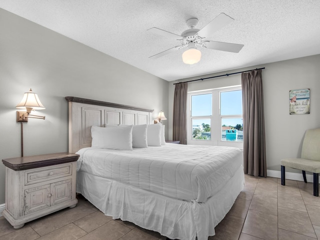 bedroom featuring baseboards, a ceiling fan, a textured ceiling, and light tile patterned flooring