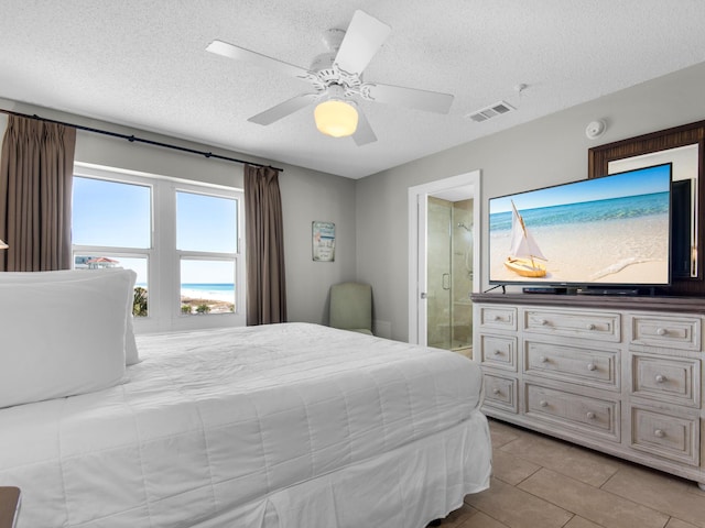tiled bedroom featuring a ceiling fan, a textured ceiling, visible vents, and ensuite bathroom