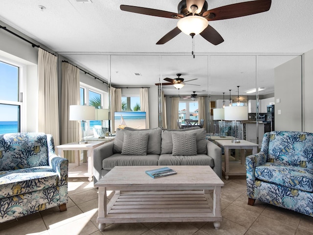 living room featuring tile patterned floors, ceiling fan, and a textured ceiling