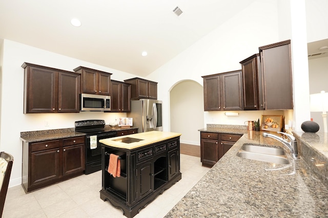 614 Red Fern Rd, Crestview, FL 32536 - kitchen featuring appliances with stainless steel finishes, a sink, arched walkways, lofted ceiling, and light stone countertops