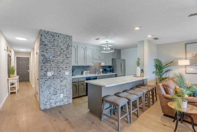 300 Cain Rd Unit 320, Panama City Beach, FL 32413 - kitchen featuring appliances with stainless steel finishes, light wood-type flooring, light countertops, a peninsula, and a breakfast bar
