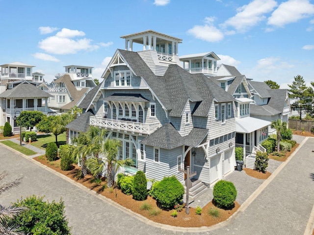 view of front of property with an attached garage, a shingled roof, driveway, and a residential view