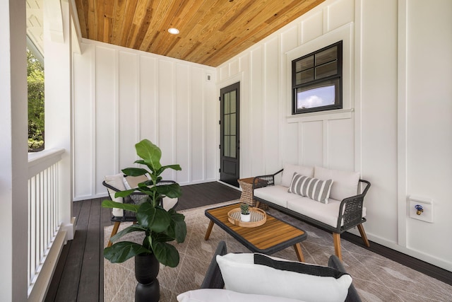 living room with wood ceiling, a decorative wall, and wood finished floors