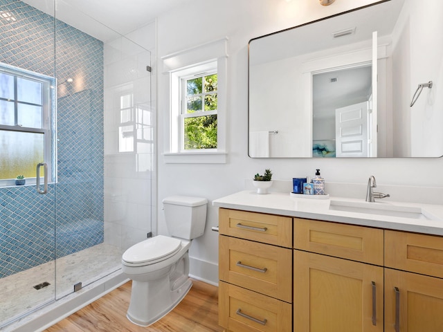 bathroom featuring toilet, wood finished floors, vanity, visible vents, and a stall shower