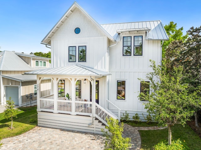 modern farmhouse style home featuring board and batten siding, a porch, and a standing seam roof