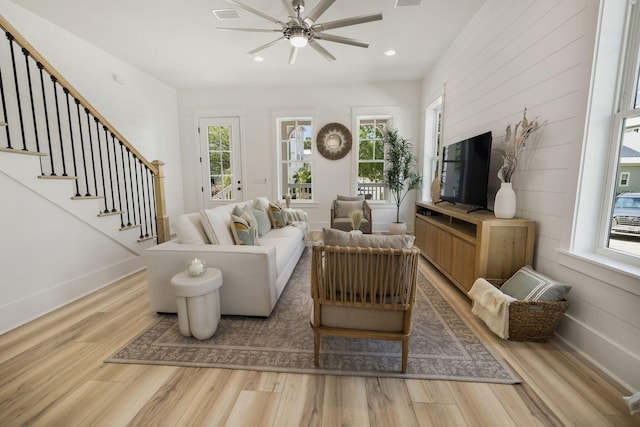 living room with a ceiling fan, baseboards, stairway, and wood finished floors