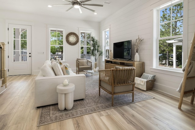 living area with wood walls, recessed lighting, light wood finished floors, a ceiling fan, and baseboards