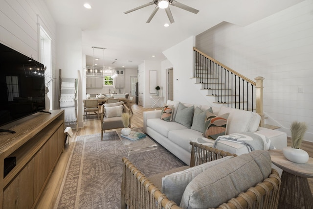 living room with light wood finished floors, recessed lighting, a ceiling fan, and stairs