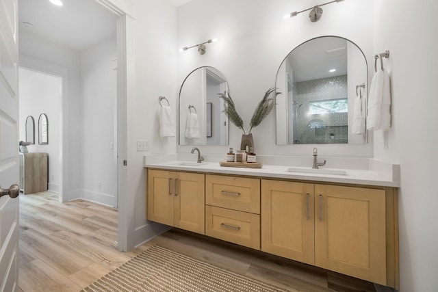 bathroom with a sink, double vanity, a walk in shower, and wood finished floors