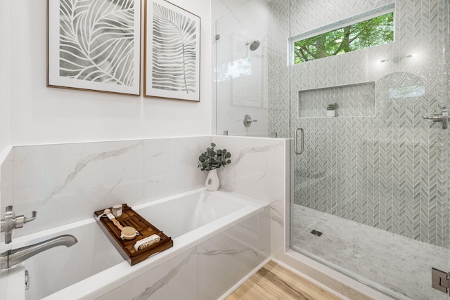 bathroom featuring a garden tub, a shower stall, and wood finished floors