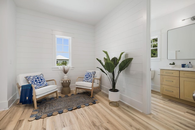 living area featuring baseboards, wooden walls, and light wood-type flooring