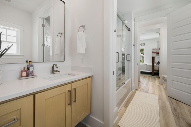 full bath with connected bathroom, toilet, wood finished floors, bath / shower combo with glass door, and vanity