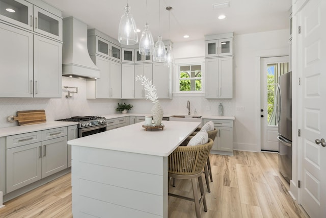 kitchen with stainless steel appliances, a sink, custom range hood, light countertops, and gray cabinets