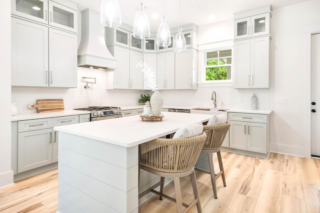 174 Grande Pointe Cir, Inlet Beach, FL 32461 - kitchen with custom range hood, a center island, a breakfast bar area, tasteful backsplash, and light countertops